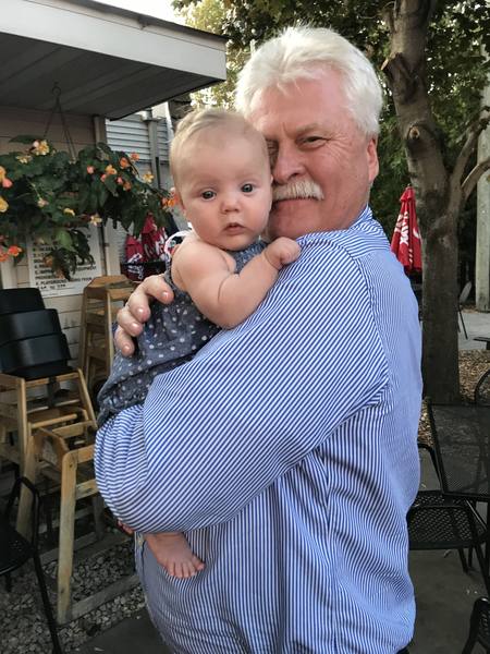 Gary holding his grandchild outdoors